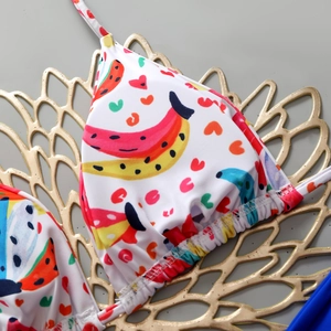 Detail of white bikini top with tropical fruit patterns and halter neck tie design