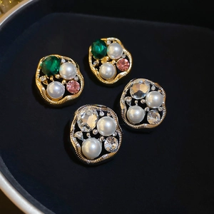 Detailed macro view of vintage pearl stud earrings with crystal inlays on black velvet