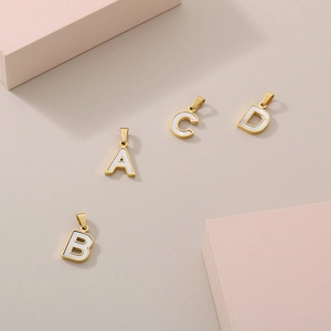 Detailed macro view of 18K gold plated alphabet charms with white shell inlay A B C D