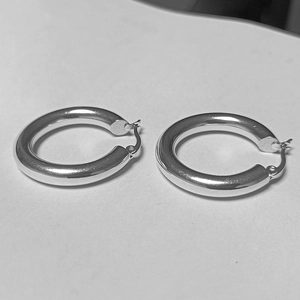 Gros plan de boucles d'oreilles créoles en acier inoxydable argenté poli avec fermoir