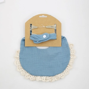 Blue cotton muslin baby bib with beige lace trim and matching headband set on card
