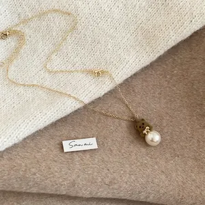 Close-up of a velvet bear pendant necklace with a large pearl on a cozy knitted background