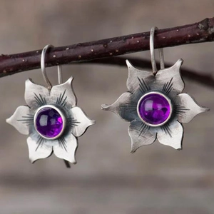 Détail de boucles d'oreilles fleur avec pierres violettes en finition argent vieilli