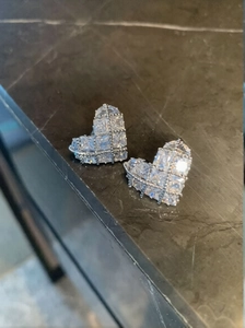Detailed close-up of heart-shaped checkered stud earrings with zircon inlay on dark stone