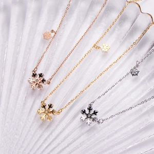Three snowflake necklaces in rose gold, gold, and silver finishes with crystal accents