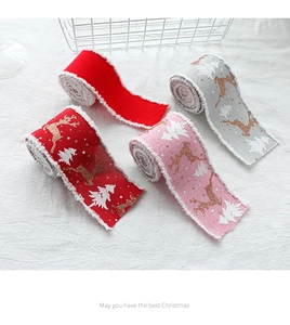 Detail of Christmas ribbons with reindeer prints and white fuzzy edges on linen fabric