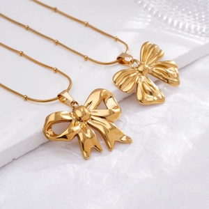 Elegant 18K gold-plated titanium steel bow necklace on minimalist white stone background