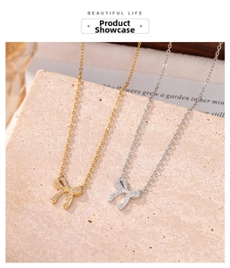 Detailed macro view of gold and silver bow necklaces with zircon pavé on stone surface