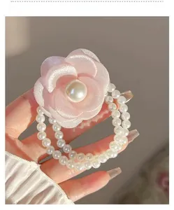 Detailed shot of pink fabric camellia flower with pearl center and double pearl hair band
