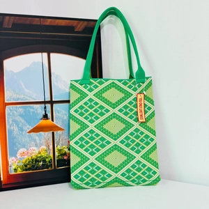 Detail of green and white geometric woven tote bag with a patterned fabric shoulder strap