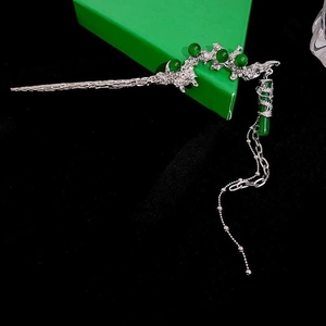 Detailed macro view of silver dragon hair pin with green beads and dangling tassels