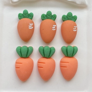 Detailed view of DIY resin carrot charms with orange bodies and green leafy tops