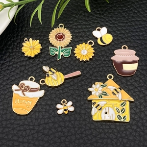 Detailed enamel bee and sunflower charms laid on black leather for DIY jewelry making