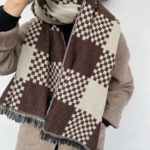 Detail of checkered knit scarf in brown and beige with fringed edges and thick texture