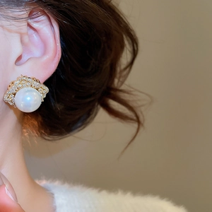 Macro detail of elegant pearl earring with zirconia accents worn by a model