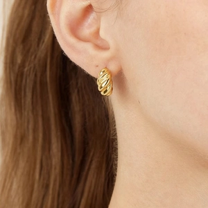 Elegant gold twisted hoop earrings worn by a model showcasing a modern luxury design