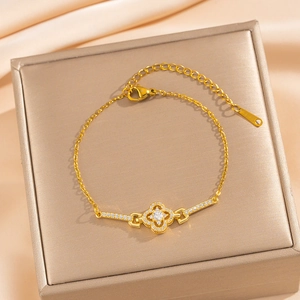 Gold-plated four-leaf clover bracelet with sparkling crystals on champagne silk background