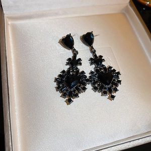 Macro shot of gothic black heart earrings with set stones in a jewelry box