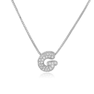 Macro detail of silver tone bubble letter G pendant with cubic zirconia on box chain necklace