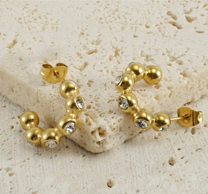 Gros plan de boucles d'oreilles dorées en U avec diamants sur socle en pierre