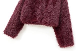 Detail of wine red faux fur jacket showing fluffy texture on cuffs and hemline