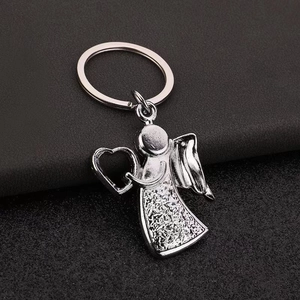 Detailed view of silver metal angel keychain with heart and textured honeycomb dress