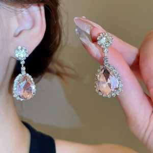 Close-up of elegant pink teardrop earrings with halo diamond setting on model