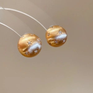 Macro shot of 18k gold plated brushed metal stud earrings with star engraving