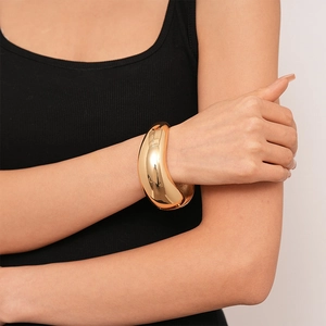 Close-up of golden wide twisted irregular geometric cuff bracelet on model's wrist