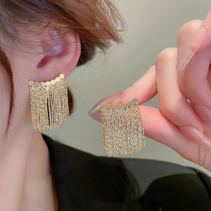 Gros plan de boucles d'oreilles dorées à franges en éventail sur un modèle élégant