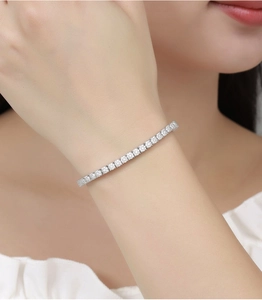Detailed close-up of silver-tone tennis bracelet with claw-set clear stones on wrist