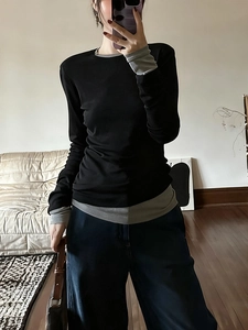 Minimalist black long-sleeve T-shirt with grey patchwork detailing in a home setting
