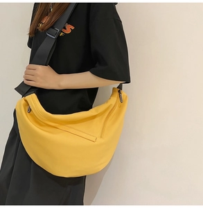 Detailed view of a yellow canvas crossbody dumpling bag worn by a model in casual style