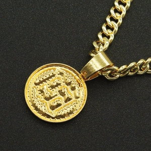 Detailed macro view of a gold-toned Cuban chain necklace with a rhinestone round pendant