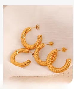 Detailed macro view of textured gold C-shaped hoop earrings with hammered and ribbed finishes