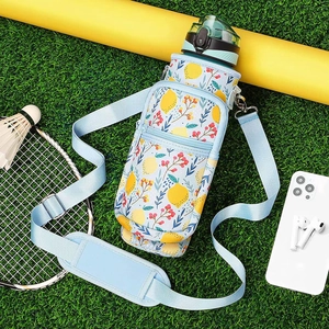 Detail of insulated water bottle sleeve with lemon pattern and adjustable blue strap on grass