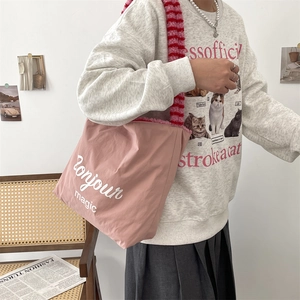 Pink tote bag detail with red striped plush strap and Bonjour magic text print