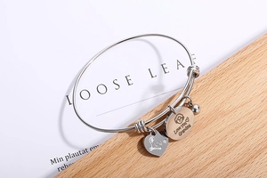 Macro detail of silver adjustable wire bracelet with Love You Grandma and heart pendants