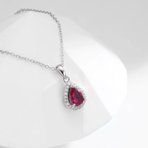 Macro shot of silver pear-cut red crystal pendant surrounded by white zircon stones