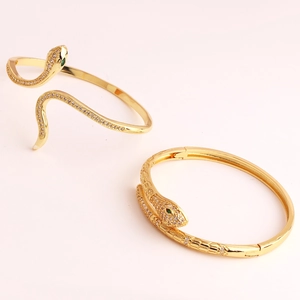 Macro detail of gold snake bracelet with white zircon pave and emerald green gem eyes