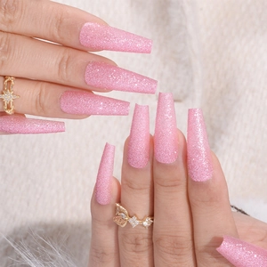 Sparkly pink glitter long coffin press-on nails shown on hands with a soft background