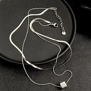 Close-up of double-layered silver chain necklace with cube pendant and lobster clasp
