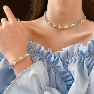 Gros plan d'un ensemble de bijoux aigue-marine et perles porté par un mannequin