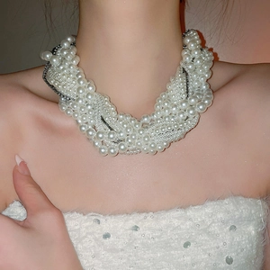 Detail view of a multi-layer knotted pearl necklace on a model showing the clavicle length