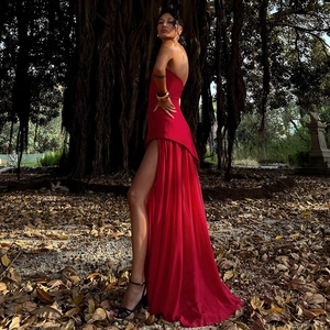 Détail de la robe maxi rouge élégante à épaules dénudées avec fente dans la forêt