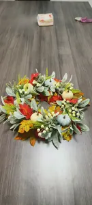 Detailed view of autumn wreath with maple leaves and pumpkins on a dark wood background