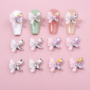 3D resin butterfly nail charms with rhinestones and pearls shown on various nails