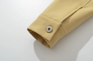 Macro detail of khaki jacket cuff featuring twill fabric texture and silver metal snap button