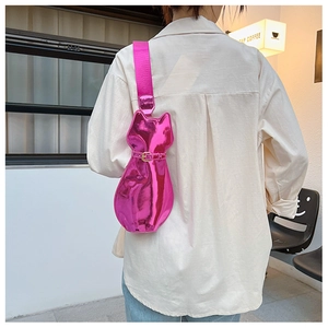 Detail of bright pink metallic cat-shaped crossbody bag with wide strap on a model