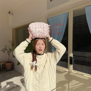 Pink floral fabric cosmetic bag with rectangular woven label held by a female model